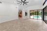High ceilings with a multi-blade ceiling fan, large-format tile flooring, and expansive sliding glass doors opening to a private pool