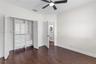 Wood-finish flooring, custom built-in closet cabinetry with drawers and shelving, and a matte black ceiling fan