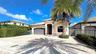 Single-story residence featuring a tile roof, stucco exterior, decorative stone trim, arched entryway, and a paver driveway
