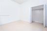 Neutral-toned large-format tile flooring, high ceilings, and closet with white paneled bi-fold doors featuring an integrated metal rod and shelf