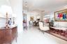 Open-concept interior featuring large-format tile flooring, recessed tray ceiling, arched architectural detailing, and ornate crystal chandelier light