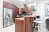 Kitchen featuring dark wood cabinetry, stone countertops, stainless steel appliances, a central island with decorative corbels, and tile flooring