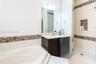 Bathroom featuring a soaking tub, glass-enclosed shower with a tiled recessed niche, vanity with a stone countertop, and decorative mosaic tile accent