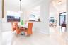 Dining area featuring large-format tile flooring, a suspended drum pendant light, and a pass-through opening