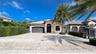 Single-story residence featuring a tile roof, arched entryway, paved driveway, and mature palm tree
