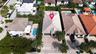 Aerial perspective of property featuring a tile roof, paved driveway, two-car garage, and established perimeter landscaping