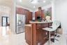 Kitchen featuring wood cabinetry, stone countertops, stainless steel appliances, a raised bar, and tile flooring