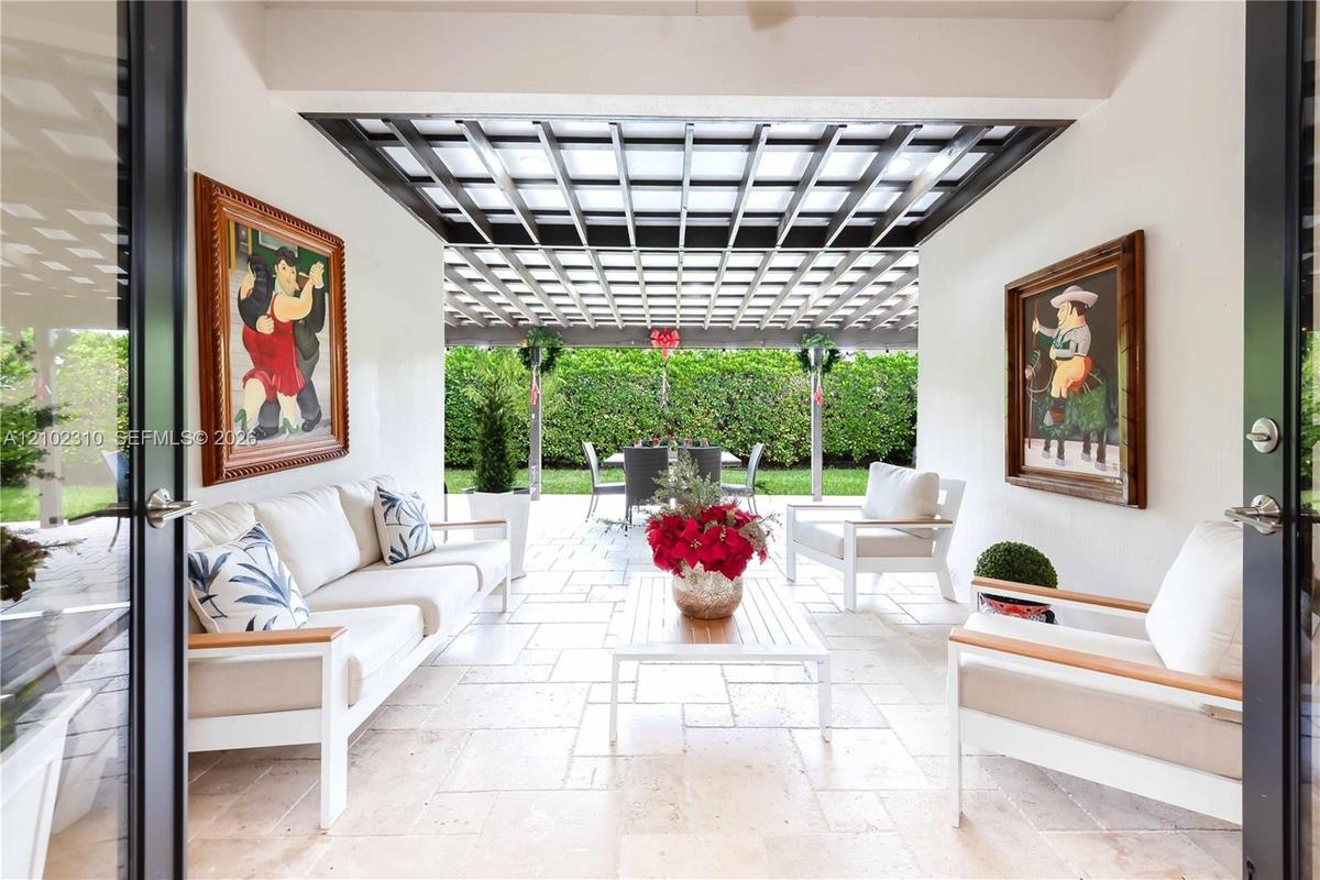 Covered patio featuring stone tile flooring, a geometric pergola ceiling structure, and matte black-framed double entry doors
