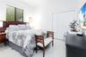 Bedroom featuring large-format tile flooring, multi-panel window with horizontal blinds, and bi-fold closet doors
