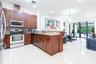 Kitchen featuring dark wood cabinetry, stone-surface countertops, stainless steel appliances, and tile flooring