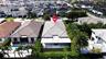 Aerial perspective of a residence featuring a tiled roof, a rear covered patio, and a landscaped backyard with mature palm trees