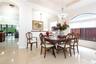 Dining area featuring polished tile flooring, a recessed tray ceiling, a multi-tiered crystal chandelier, and a large arched window