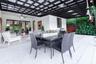 Covered patio featuring a dark-finish pergola, light-toned stone tile flooring, integrated ceiling fan, and glass French doors