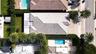 Aerial perspective of the property featuring a tile roof, paved driveway, swimming pool, and landscaped perimeter hedging