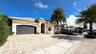 Stucco exterior residence featuring a tiled roof, arched entryway, multi-car garage, and decorative paved driveway