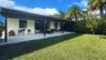 Covered patio with light-colored paver flooring, extensive flat lawn, and mature perimeter landscaping