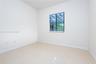 Neutral interior room featuring large-format tile flooring, crisp white walls, and a window fitted with horizontal blinds