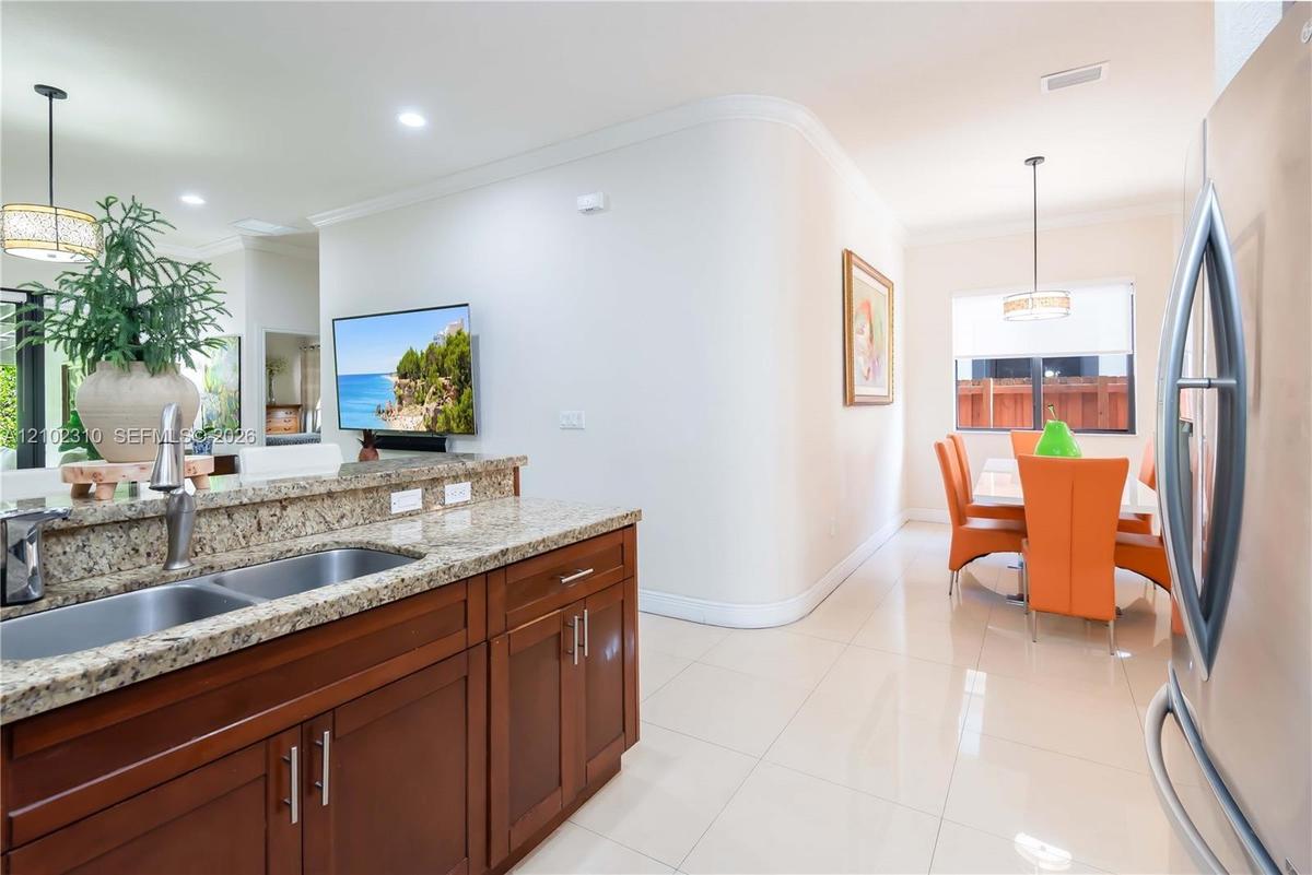 Kitchen featuring a stone-surface countertop, double-basin stainless steel sink, wood cabinetry, tile flooring, and recessed lighting