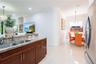 Kitchen featuring a stone-surface countertop, double-basin stainless steel sink, wood cabinetry, tile flooring, and recessed lighting