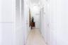 Hallway featuring neutral large-format tile flooring, multiple sets of white louvered-style closet doors, solid-panel interior doors, and crown moldin