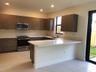 Kitchen featuring wood-finish cabinetry, stone-surface countertops, an integrated peninsula, stainless steel appliances, and tile flooring
