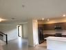 Kitchen featuring flat-panel wood-finish cabinetry, quartz countertops, a kitchen island, and stainless steel appliances, including a built-in microwa