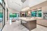 Chef’s kitchen featuring a large stone-topped island, floor-to-ceiling glass sliding doors, recessed lighting, multi-bulb pendant lighting, and built-