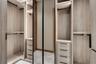 Custom walk-in closet featuring light wood-finish cabinetry, built-in drawer stacks with matte black pulls, vertical integrated LED accent lighting, f