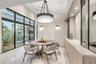 Vaulted ceilings with recessed lighting, full-height glass sliding doors, large-scale crystal and metal chandelier, built-in cabinetry with natural st