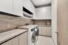 Laundry room featuring floor-to-ceiling cabinetry, stone-patterned backsplash, expansive stone-finish countertop, integrated sink with metallic faucet