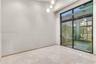 High ceilings featuring tiered globe pendant lighting, oversized sliding glass doors with dark frames, and polished neutral-toned tile flooring
