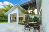 Covered patio featuring stone-tiled flooring, a built-in outdoor kitchen with stainless steel appliances, a slatted overhead architectural structure, 