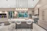 Kitchen featuring flat-panel cabinetry, a large stone-topped central island, built-in stainless steel appliances, and a multi-pendant light fixture be