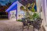 Covered outdoor patio featuring stone flooring, a slatted timber pergola, and a built-in outdoor kitchen with a stainless steel range hood