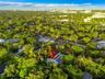 Aerial perspective showcasing a parcel characterized by dense, mature tree canopy, integrated swimming pool, and flat-roof architectural profile withi