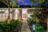 Modern contemporary facade featuring a textured stone accent wall, natural wood-finish front door, horizontal-pane garage door, overhead beam detailin