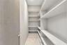 Storage area featuring custom white shelving, wood-finish door, and metal door hardware