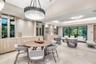 Vaulted ceilings, large-scale crystal chandelier, built-in cabinetry with light wood finish, stone-finish flooring, and floor-to-ceiling glass wall pa