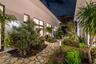 Enclosed garden courtyard featuring patterned stone pavers, desert-inspired landscaping, integrated pathway lighting, and multiple floor-to-ceiling wi