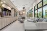 Vaulted ceilings with recessed lighting, floor-to-ceiling multi-panel glass doors, custom wall-to-wall cabinetry with stone countertops, and integrate