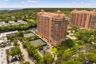 High-rise residential building featuring a terracotta facade, dome-topped roofline, integrated tennis courts, and mature landscaping