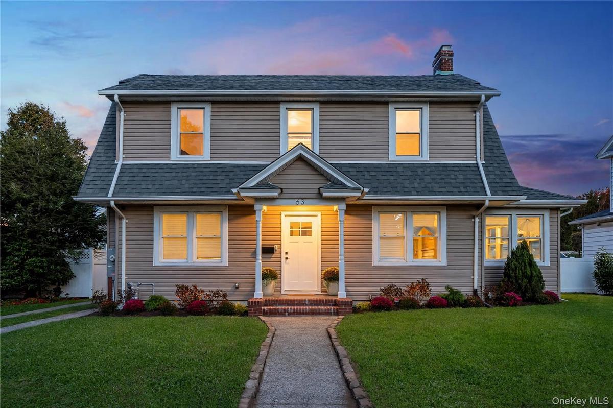 Welcome Home to 63 Mead St Hempstead! Two-story colonial exterior featuring horizontal siding, a gabled portico, brick entry steps, multi-pane windows