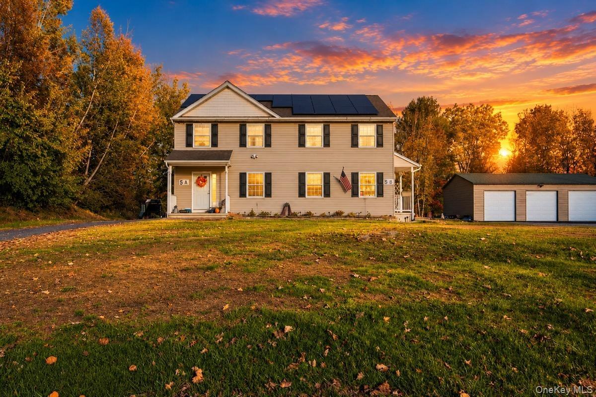 Two-story residence featuring light-colored siding, a roof-mounted solar panel array, covered entryway, and an attached three-car garage situated on a