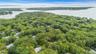 Aerial perspective featuring dense canopy coverage, established woodland surroundings, and proximity to the coastline. Close walk to the Marina and be
