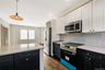Eat in Kitchen featuring two-tone navy and white shaker cabinetry, quartz countertops, stainless steel appliances, a center island, and wood-finish fl