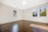 Bedroom featuring dark-stained wood-finish flooring, neutral wall paint, white trim, and multiple double-hung windows