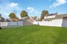 Backyard featuring a manicured lawn, detached two-car garage with electric and white vinyl privacy fencing. Grass is virtually enhanced