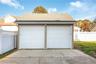 Detached two-car garage with electric featuring dual paneled overhead doors, vinyl siding, a shingled roof, and an exterior concrete apron, enclosed b