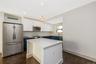 Eat in kitchen featuring two-tone navy and white shaker cabinetry, quartz countertops, stainless steel appliances, a center island, and wood-finish fl