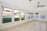 All seasons room surrounded by oversized windows, ceramic tile flooring, and a ceiling fan